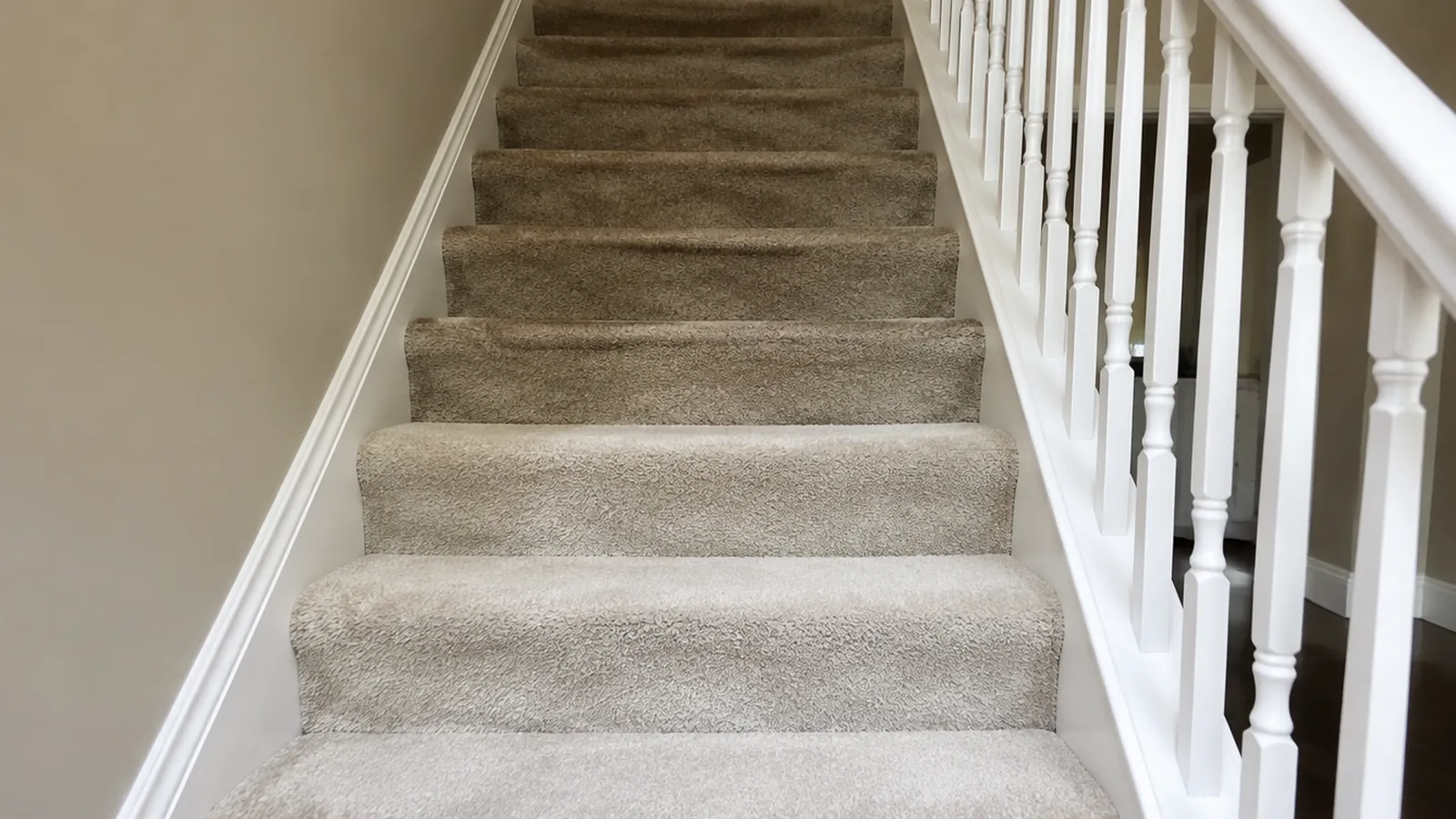Carpeted staircase with white balusters in a newer two-story home